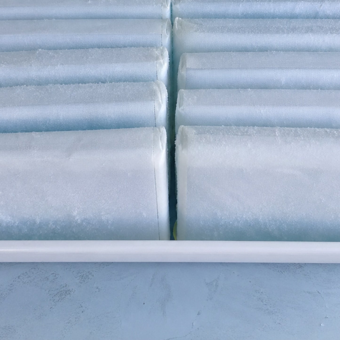Frozen gel ice packs stacked in rows, frost on the white fabric shells